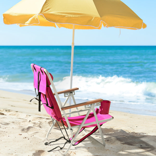 Pink beach chair set up on sandy shore under a yellow umbrella, facing the ocean waves. Ideal for outdoor relaxation and beach lounging.