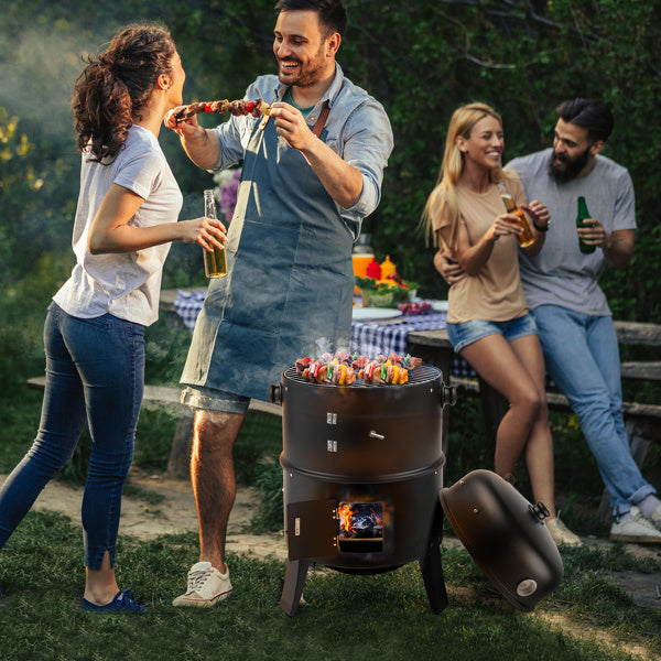 People enjoying a barbecue with the black smoked charcoal oven at an outdoor gathering.