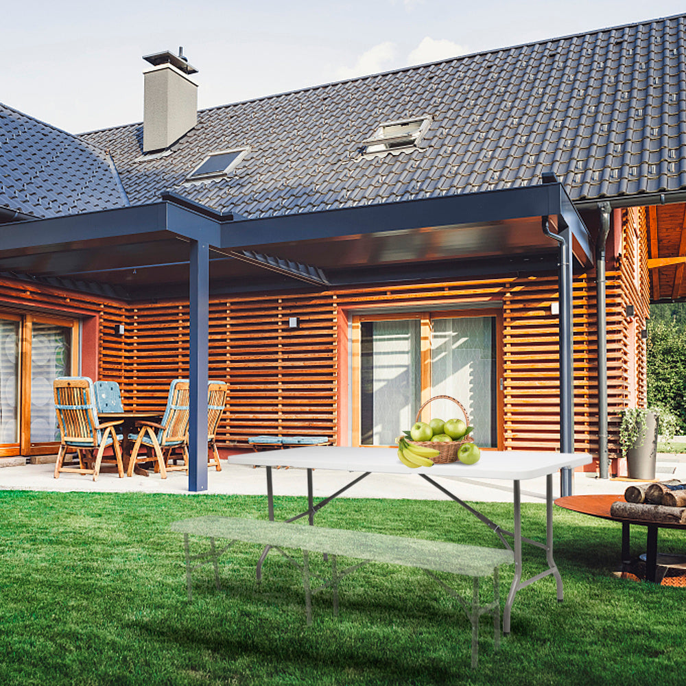 Outdoor setup featuring a plastic folding table in a backyard with a wooden house and patio furniture.