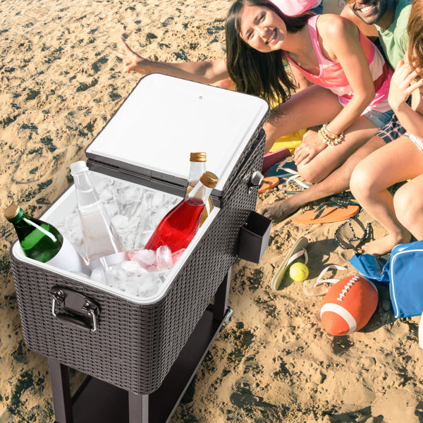 Frozen Trolley with woven rattan square leg design, filled with ice and beverages, placed on a beach with a group of friends enjoying the sun.